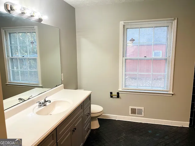 a bathroom with a sink a toilet and a window