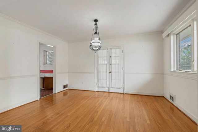 an empty room with wooden floor cabinet and windows