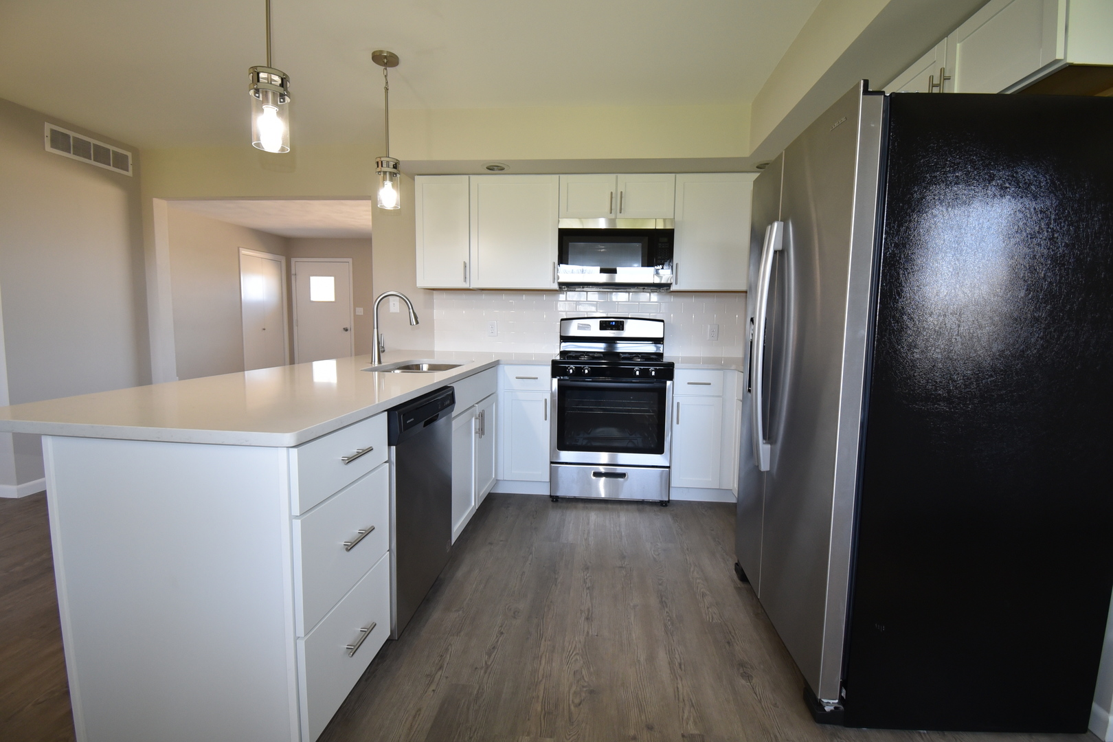 413 East Northtown Road North Normal, IL 61761 - Photo 11 of 20 a kitchen with stainless steel appliances a sink dishwasher a refrigerator a stove top oven a sink and dishwasher with wooden floor