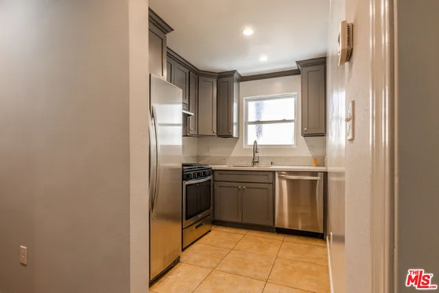 a kitchen with granite countertop stainless steel appliances a sink stove and refrigerator