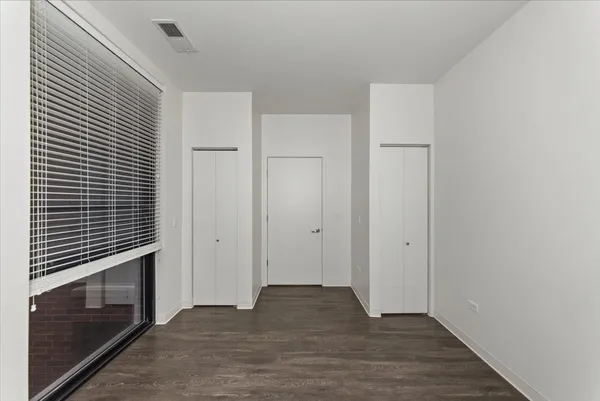 a view of an empty room with wooden floor and a fireplace
