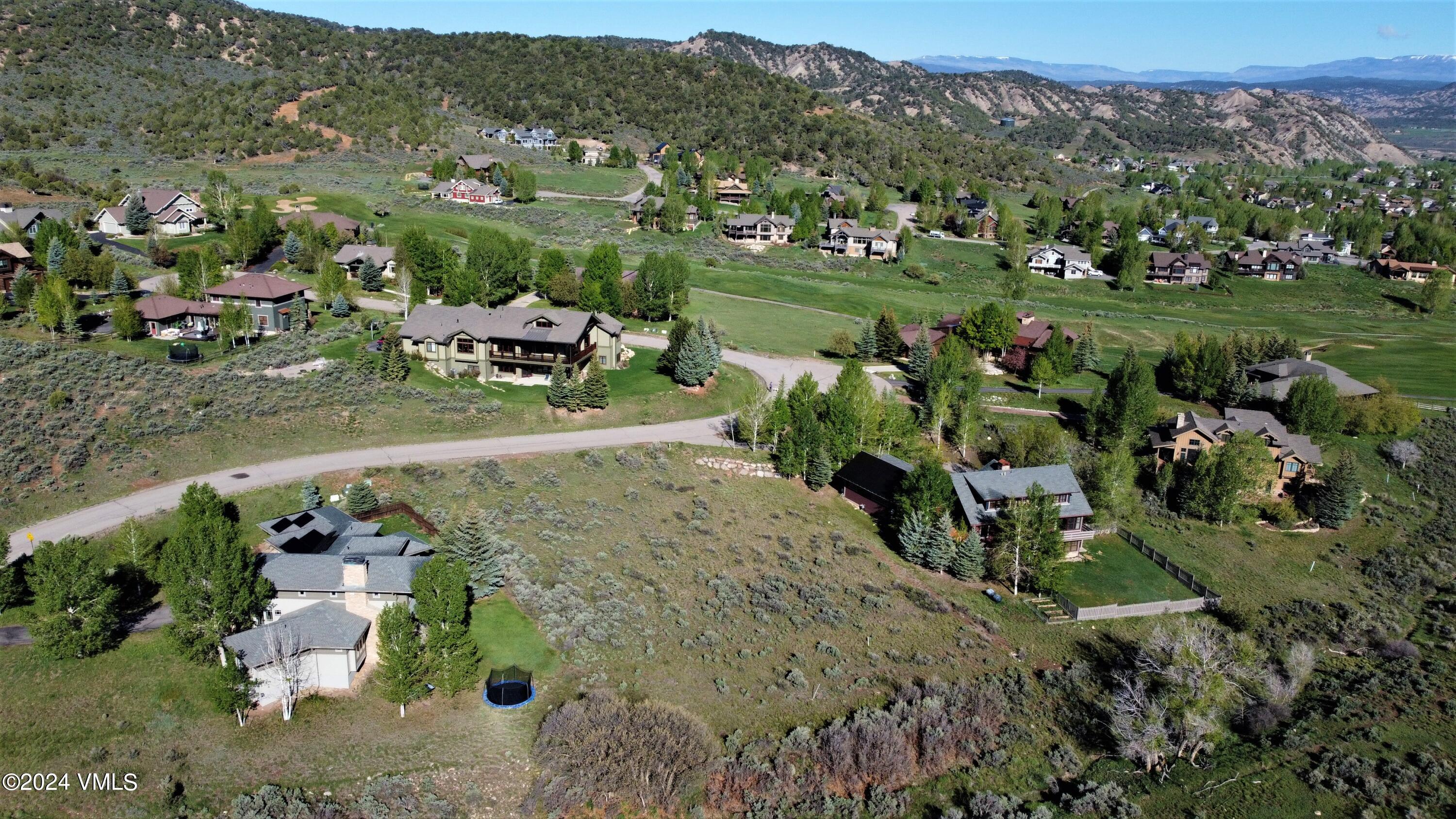an aerial view of residential houses with outdoor space and trees