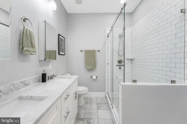 a bathroom with a granite countertop sink a toilet and shower