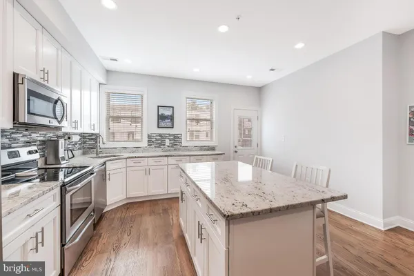 a kitchen with granite countertop stainless steel appliances sink stove microwave and cabinets