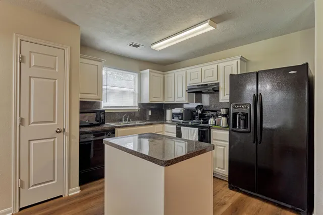 a kitchen that has a refrigerator a sink a stove a microwave and cabinets