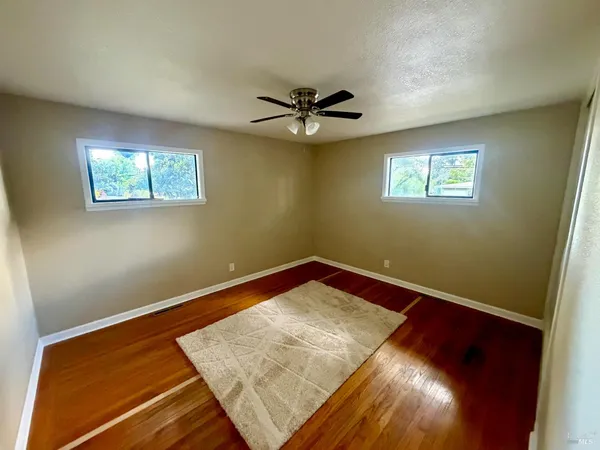 a view of a room with wooden floor and a ceiling fan