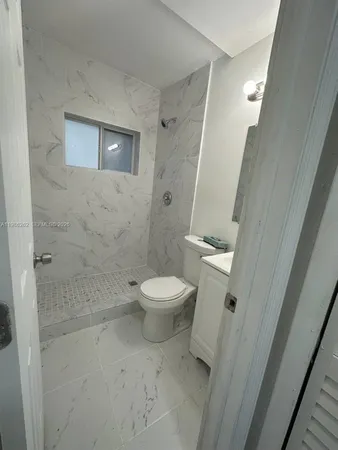 a white toilet sitting next to a bathroom sink and vanity