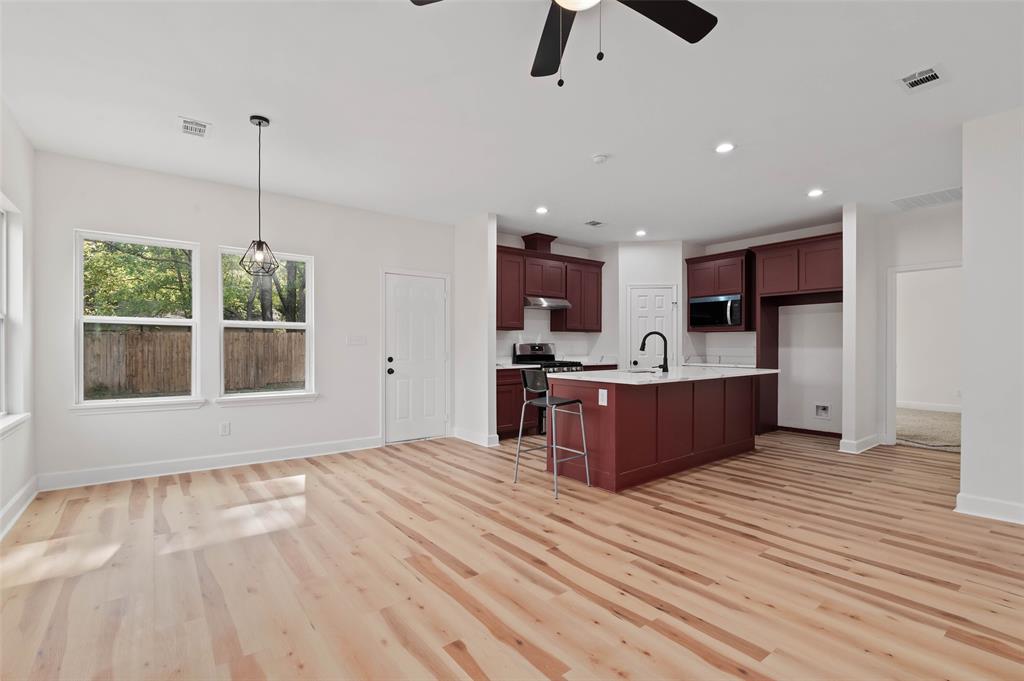 1520 Harris Street Gainesville, TX 76240 - Photo 11 of 24 a large kitchen with stainless steel appliances kitchen island granite countertop a stove top oven a sink dishwasher a dining table and chairs with wooden floor