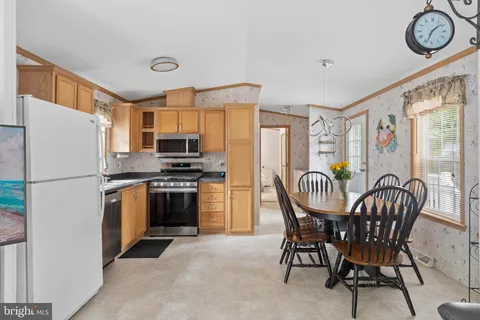 a kitchen with stainless steel appliances granite countertop a stove a refrigerator a dining table and chairs with wooden floor