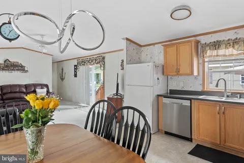 a kitchen with stainless steel appliances granite countertop a refrigerator a sink a stove and a dining table
