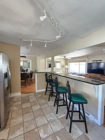 a room with stainless steel appliances kitchen island granite countertop dining table chair and a refrigerator