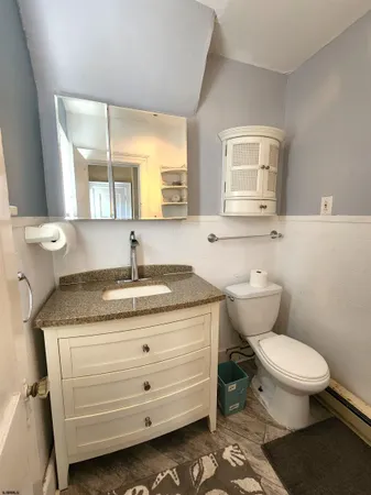 a bathroom with a granite countertop toilet sink and mirror