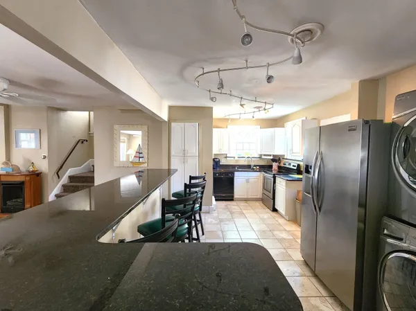 a kitchen with stainless steel appliances granite countertop a refrigerator a sink a stove and white cabinets