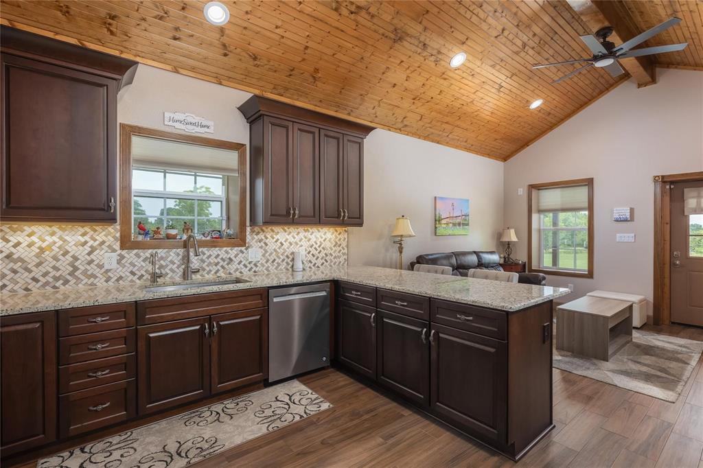 210 Spring Branch Trail North Springtown, TX 76082 - Photo 8 of 36 Kitchen featuring dark wood cabinetry, light-toned granite countertops, a herringbone mosaic tile backsplash, and stainless steel appliances