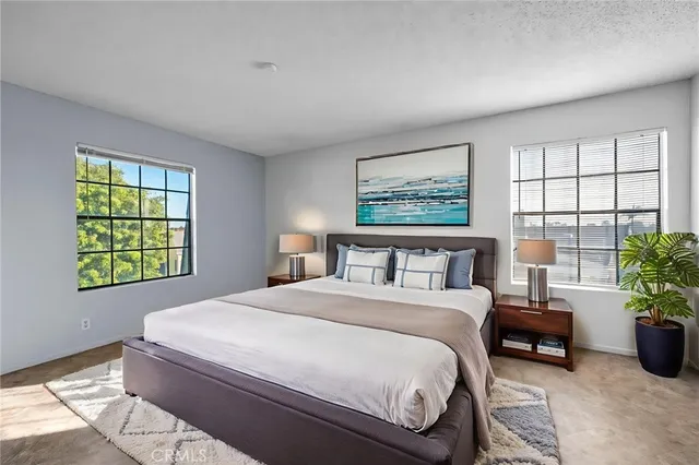 a spacious bedroom with a balcony a bed a couch and potted plant