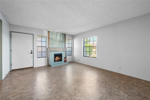 an empty room with windows and fireplace