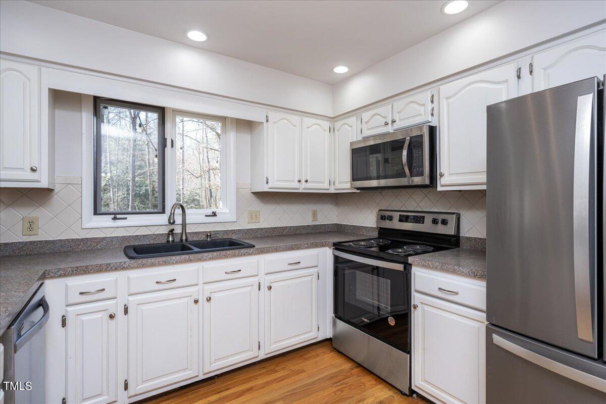 4201 Loon Lane Raleigh, NC 27616 - Photo 10 of 31 a kitchen with granite countertop white cabinets and white appliances