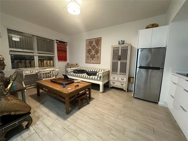 a living room with furniture gym equipment and a refrigerator