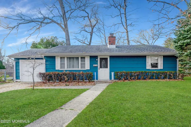 a view of a brick house with a yard chair and a large tree
