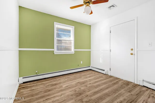 a view of empty room with wooden floor and fan