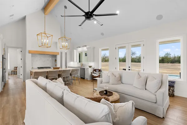a living room with furniture kitchen view and a chandelier