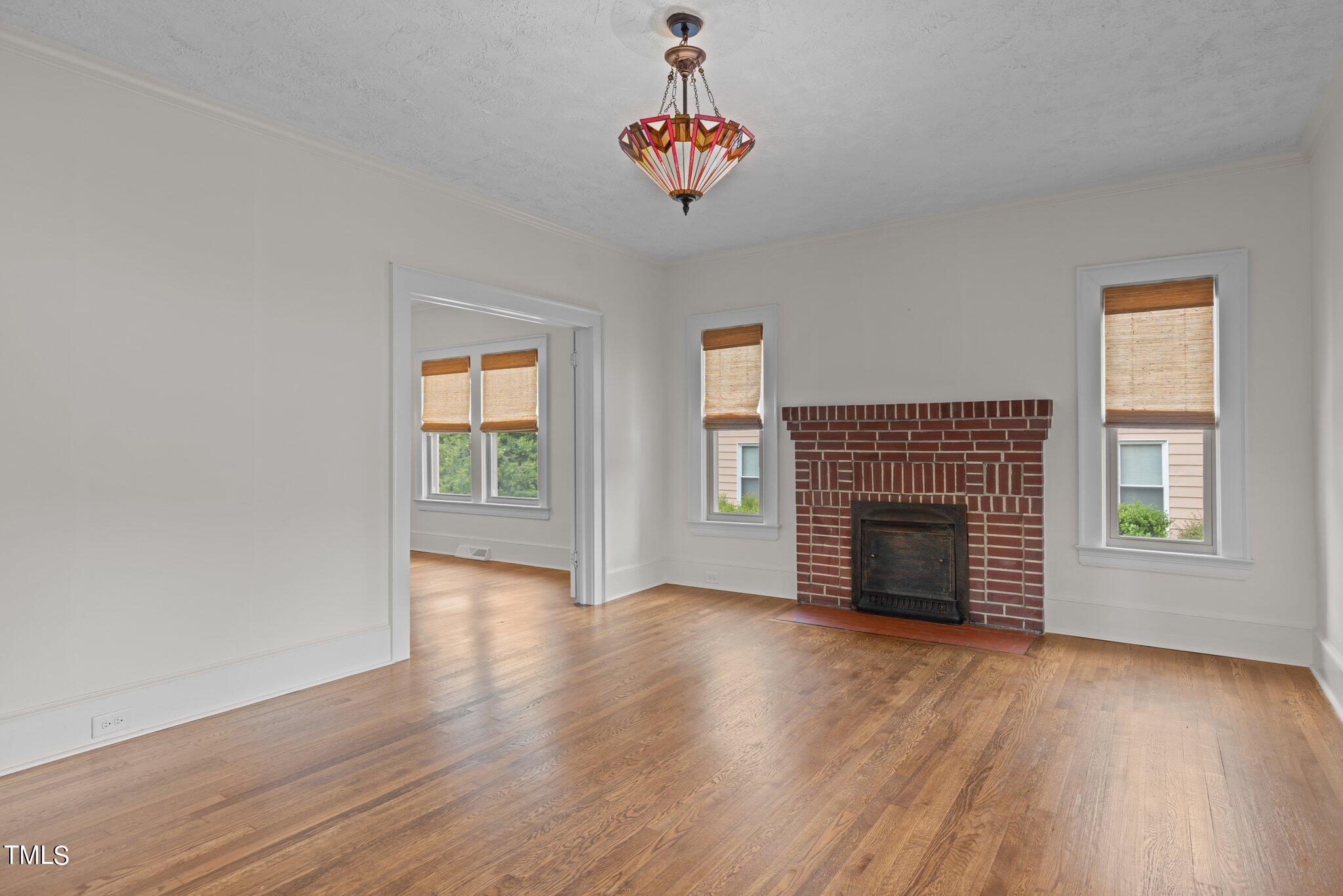 501 South Main Street Roxboro, NC 27573 - Photo 5 of 30 an empty room with wooden floor a fireplace and windows