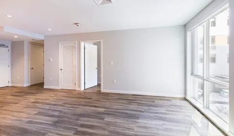 a view of an empty room with wooden floor and a window