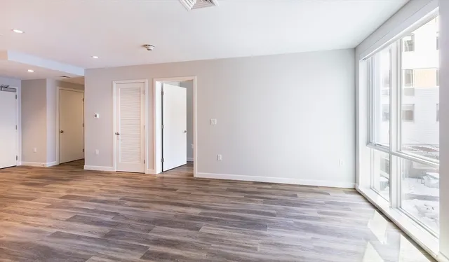 a view of an empty room with wooden floor and a window