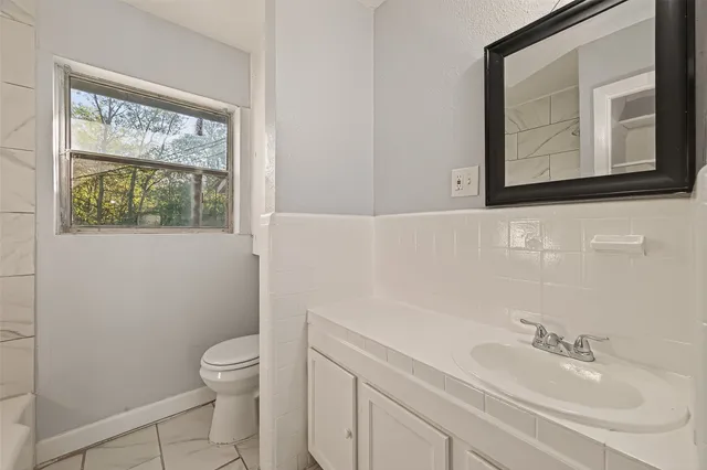 a bathroom with a toilet a sink a mirror and a window