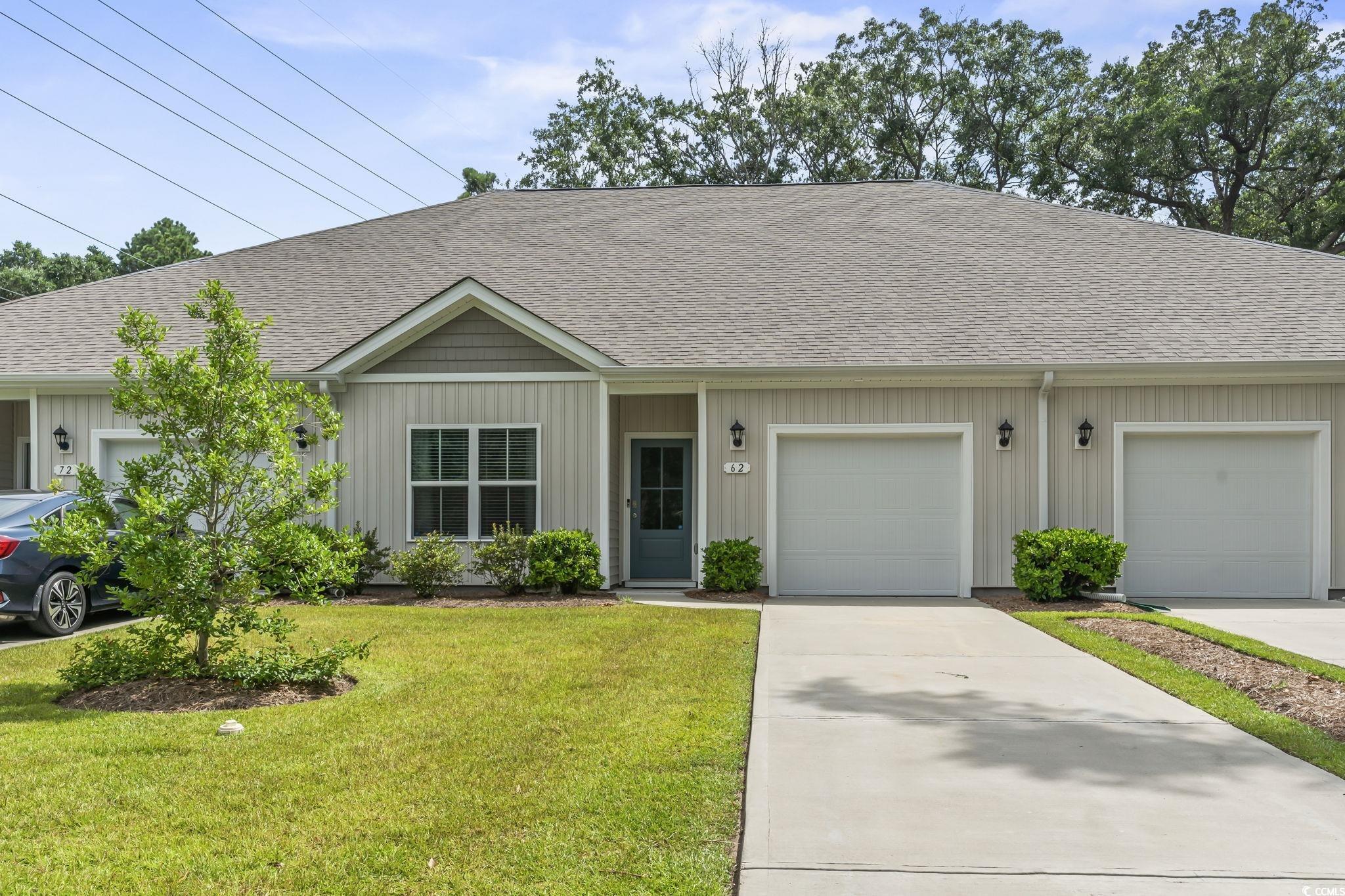 View of front of property featuring a shingled roof, a front yard, driveway, a garage, and board and batten siding