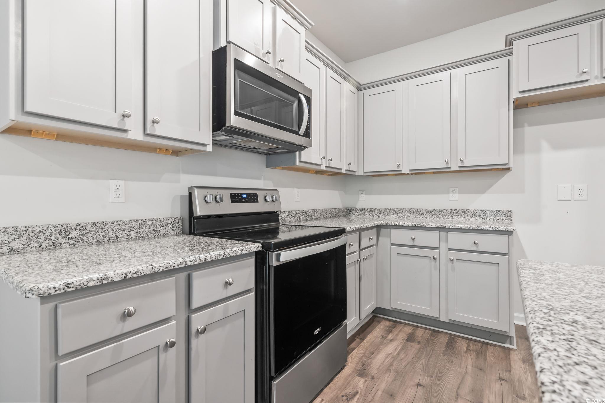 62 Sea Shell Drive, Unit 62 Murrells Inlet, SC 29576 - Photo 11 of 34 Kitchen with appliances with stainless steel finishes, wood finished floors, gray cabinets, and light stone counters