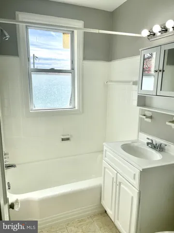 a bathroom with a sink mirror vanity and bathtub