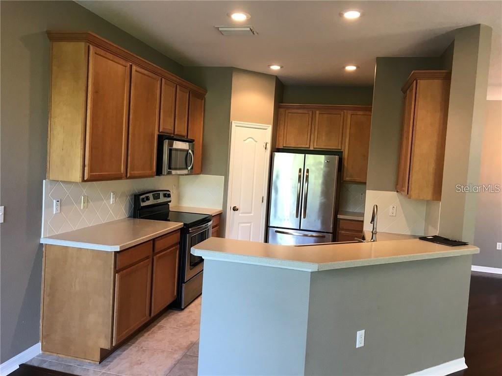 7542 Red Mill Circle New Port Richey, FL 34653 - Photo 12 of 27 a kitchen with kitchen island granite countertop a sink stove and refrigerator