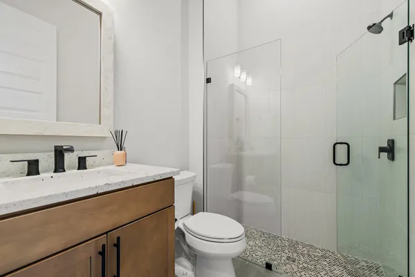 a bathroom with a toilet sink vanity and shower