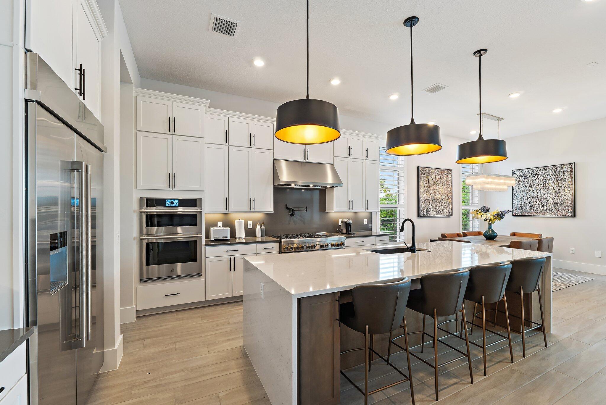 20049 Southeast Bridgewater Drive Jupiter, FL 33458 - Photo 55 of 77 a kitchen with stainless steel appliances granite countertop a stove a refrigerator a oven a sink with a dining table and chairs