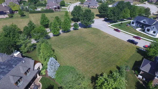 an aerial view of residential houses with outdoor space and trees