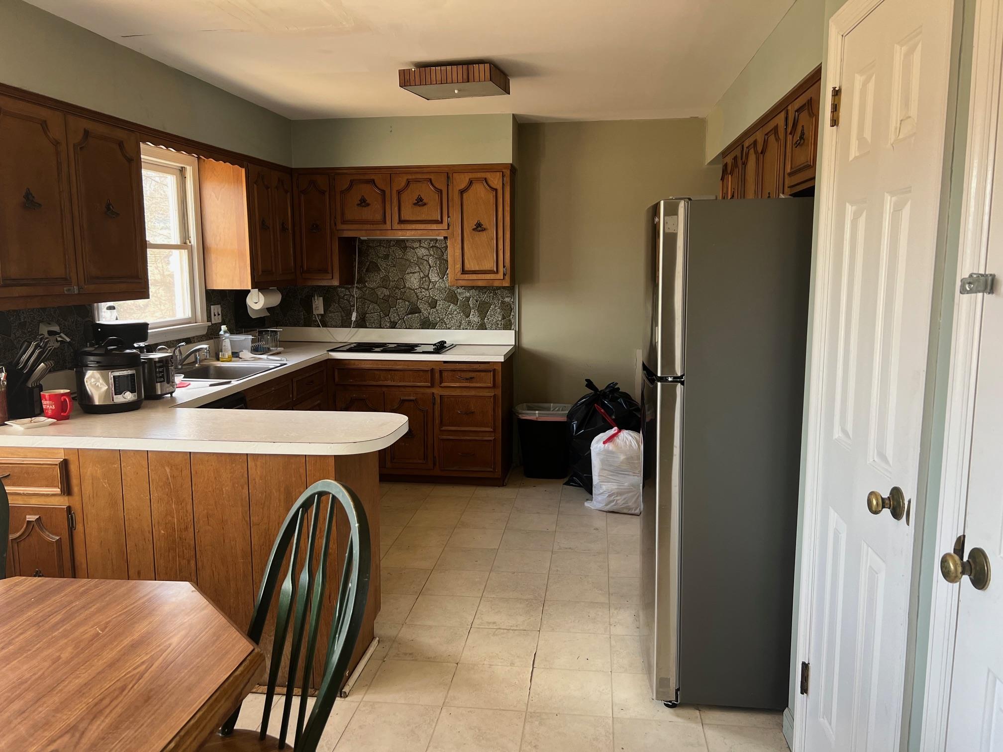 15 Old Field Road Setauket, NY 11733 - Photo 4 of 12 Kitchen with freestanding refrigerator, a peninsula, light countertops, decorative backsplash, and black electric stovetop