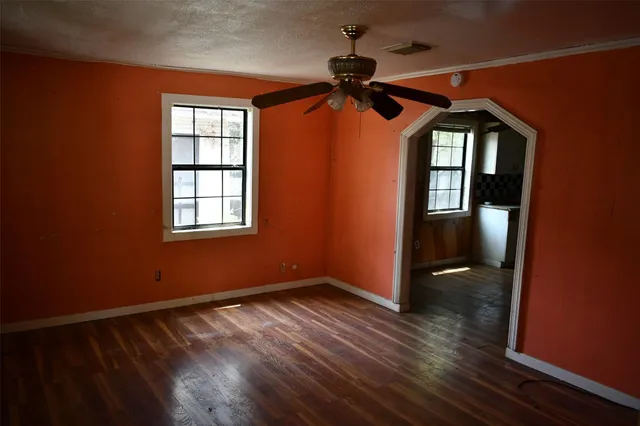 a view of empty room with wooden floor and fan