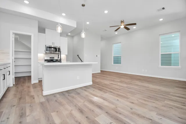 a view of a kitchen with kitchen island a sink stainless steel appliances and cabinets