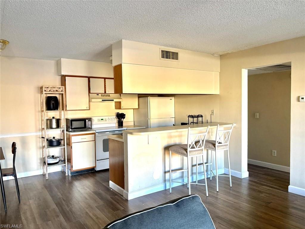 5315 Summerlin Road, Unit 1508 Fort Myers, FL 33919 - Photo 19 of 46 a kitchen with white cabinets and wooden floor