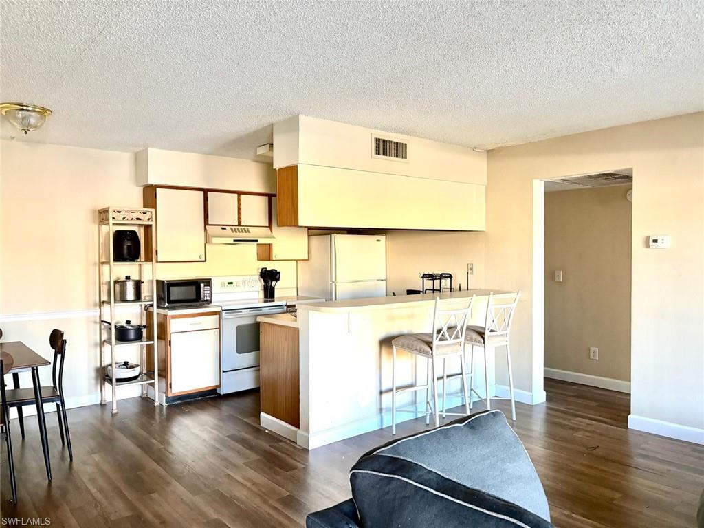 5315 Summerlin Road, Unit 1508 Fort Myers, FL 33919 - Photo 34 of 46 a kitchen with stainless steel appliances a stove a sink and white walls with wooden floors