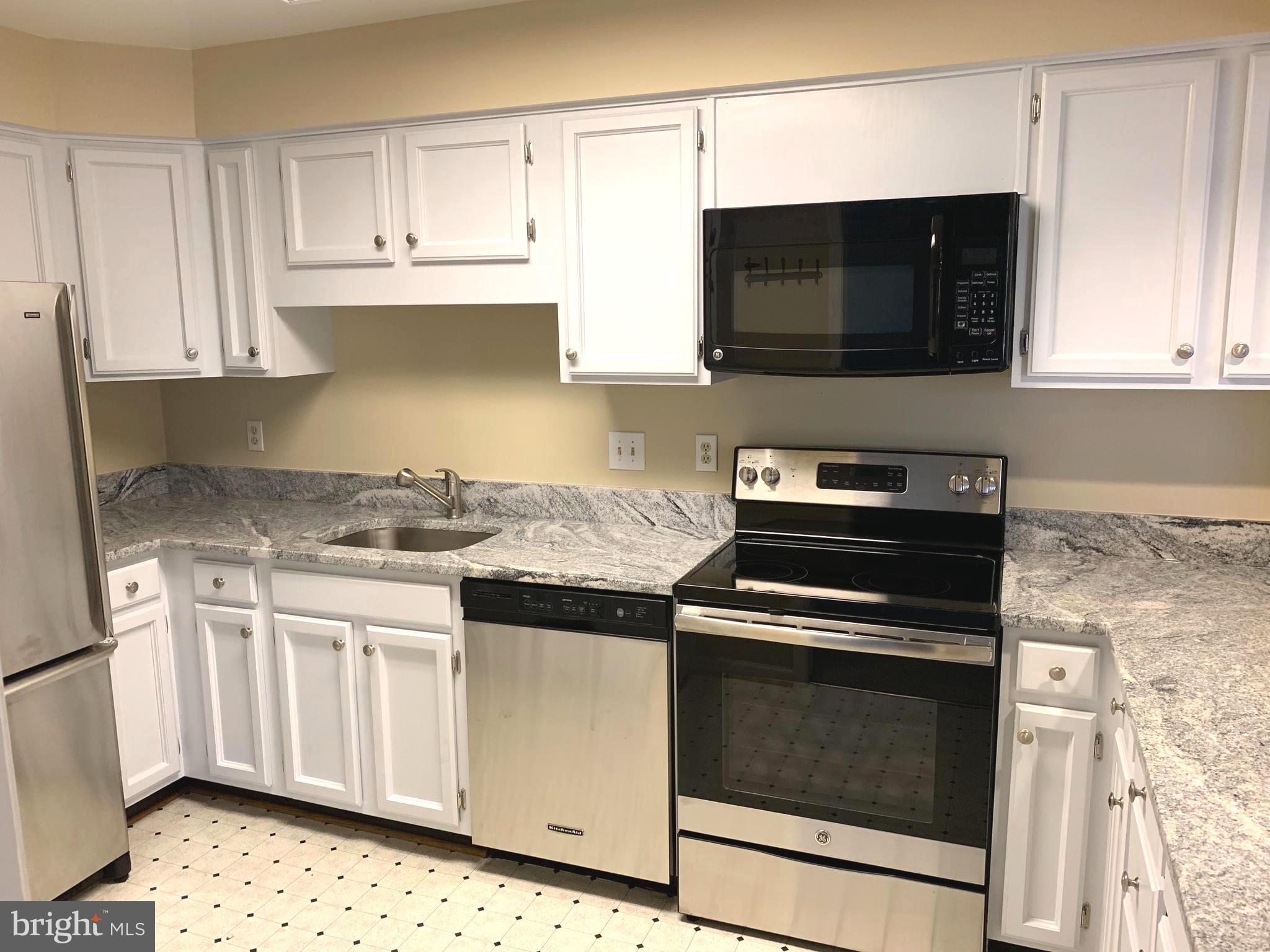 10715 Kings Riding Way, Unit 202 North Bethesda, MD 20852 - Photo 3 of 17 a kitchen with stainless steel appliances a stove a microwave and cabinets