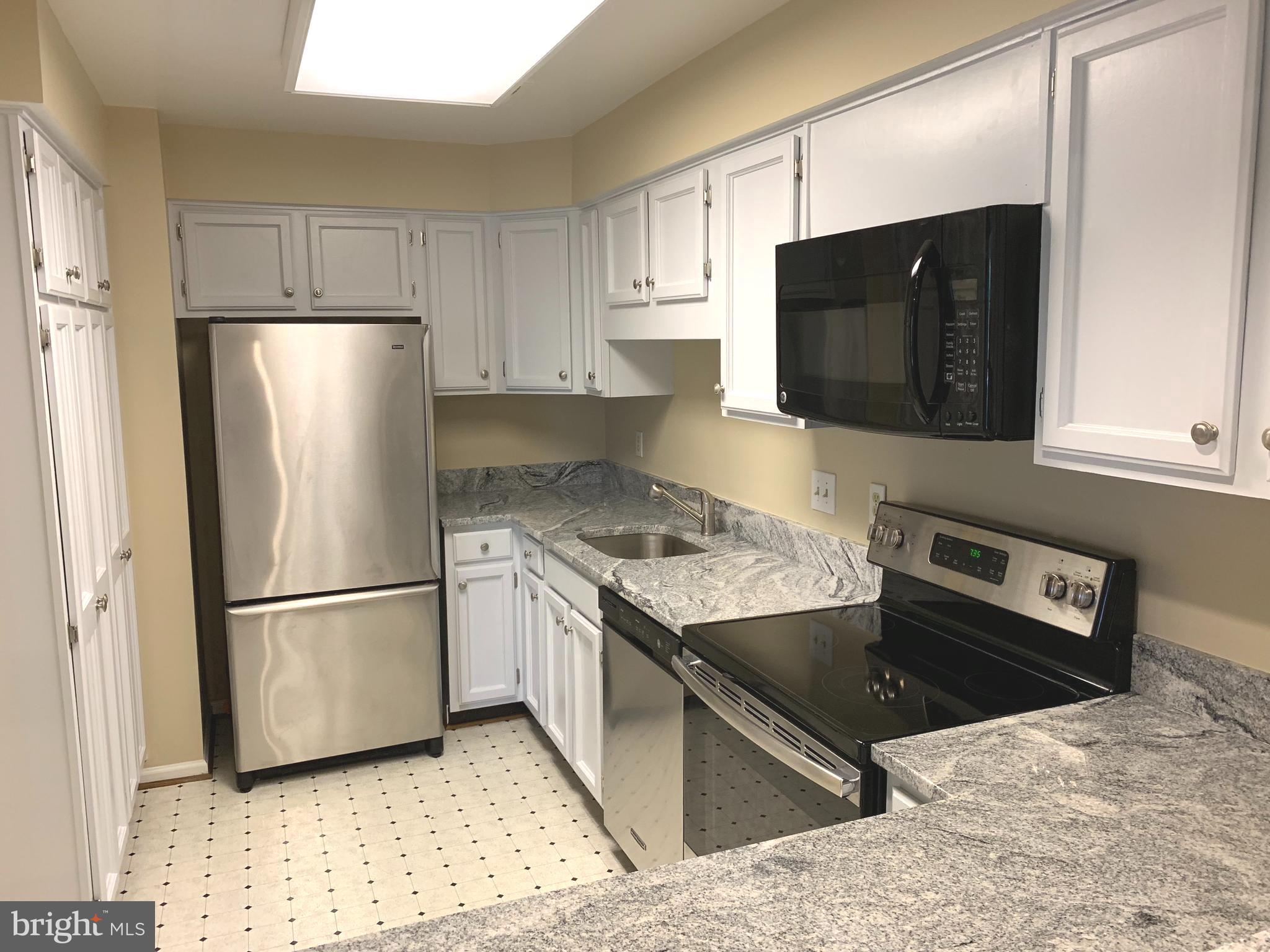 10715 Kings Riding Way, Unit 202 North Bethesda, MD 20852 - Photo 4 of 17 a kitchen with stainless steel appliances granite countertop a refrigerator stove and microwave