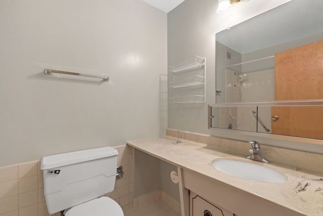 8809 West Golf Road, Unit 2B Niles, IL 60714 - Photo 11 of 17 a bathroom with a granite countertop sink mirror vanity and toilet