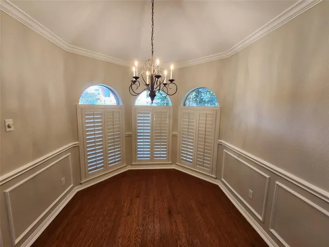 a view of a hallway with wooden floor and chandelier