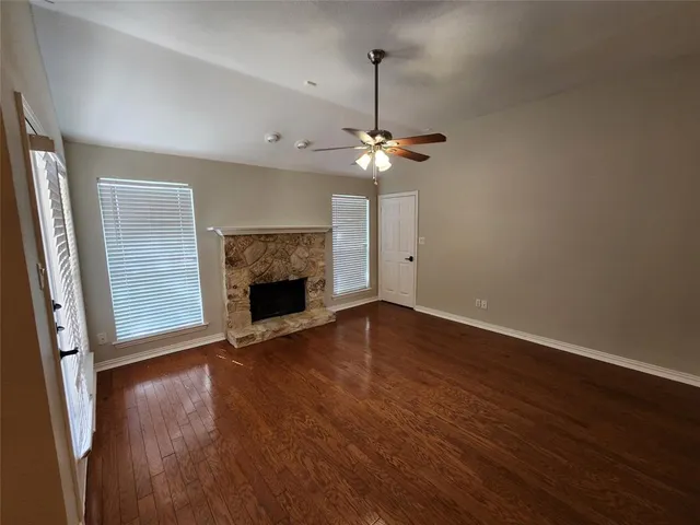 an empty room with wooden floor a ceiling fan and a window