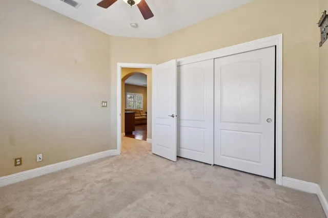 an empty room with closet and a chandelier fan