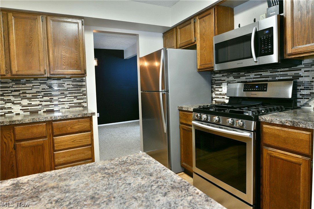4251 Wayne Road Mantua, OH 44255 - Photo 11 of 34 Kitchen featuring stainless steel appliances, tasteful backsplash, wood finish cabinetry, and dark countertops