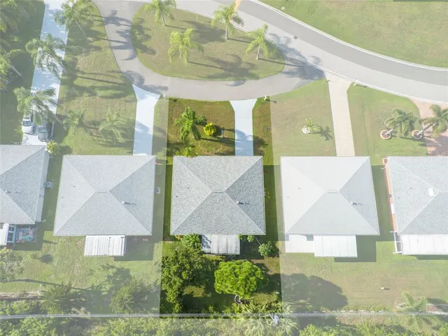 an aerial view of a residential houses with outdoor space and trees