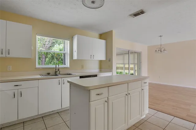a kitchen with white cabinets appliances a sink and a window